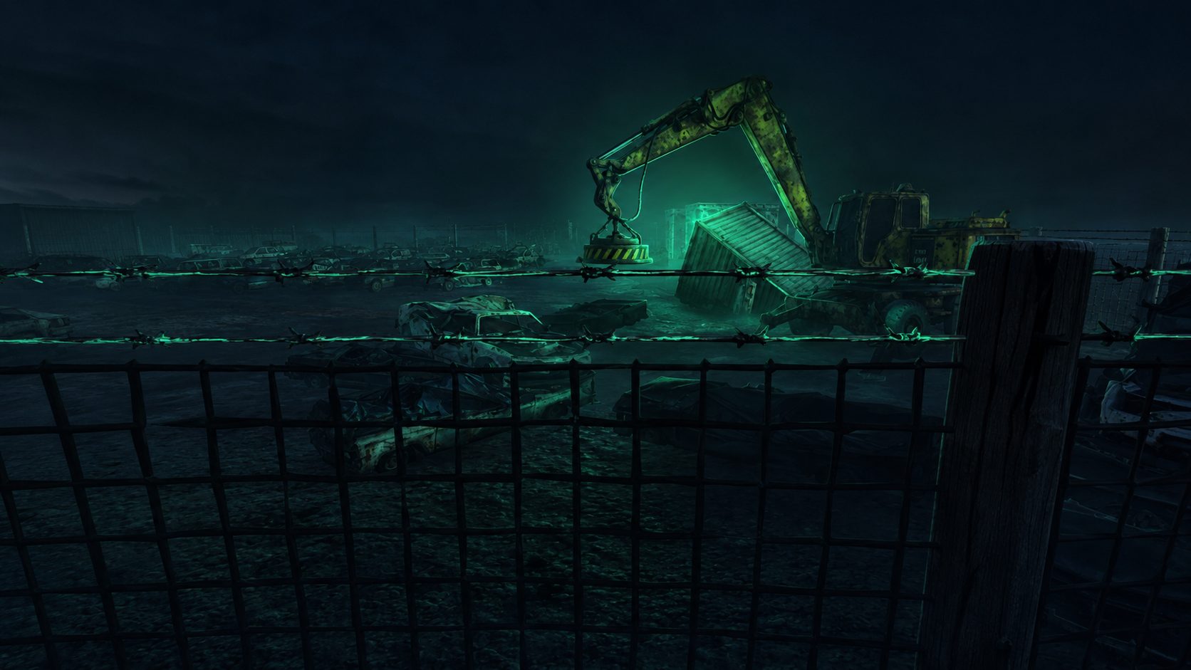 The magnet crane and shipping container in the scrapyard at night, seen through a barbed-wire fenceline glowing green