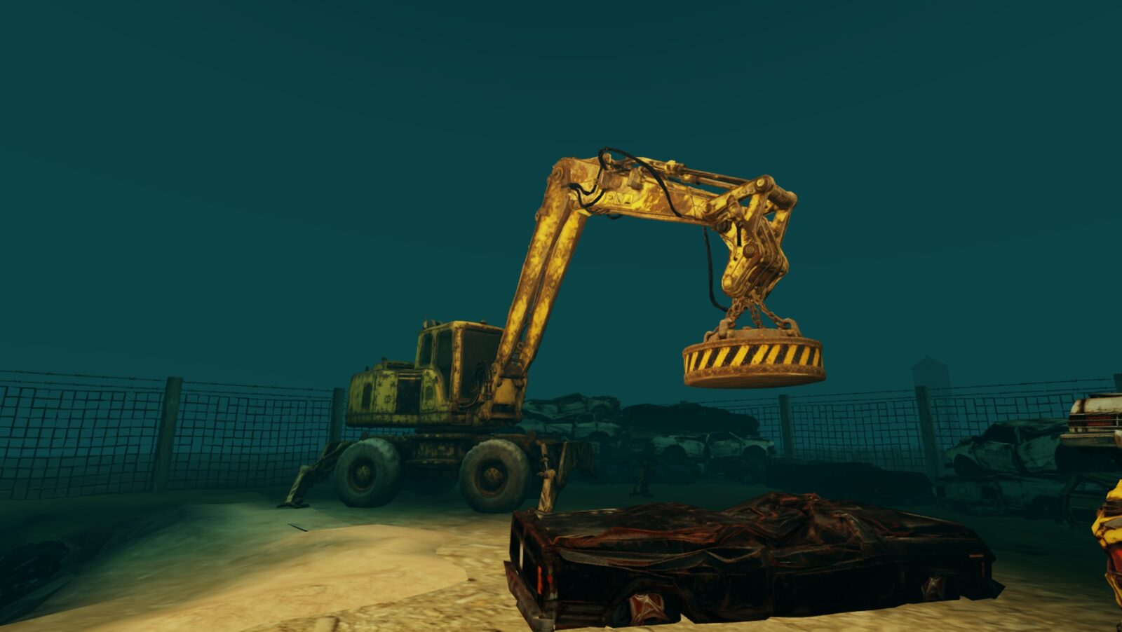 The rusted magnet crane in the scrapyard at night, lit, a crushed car in front
